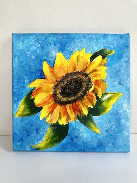 A single sunflower in close-up against a bright blue background.